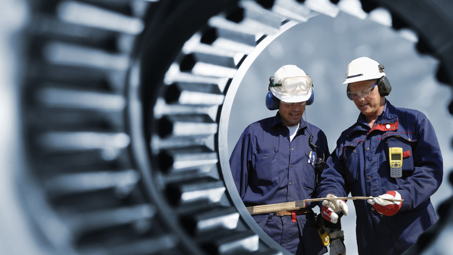 2 Bauplaner durch ein Stahlrohr fotografiert.