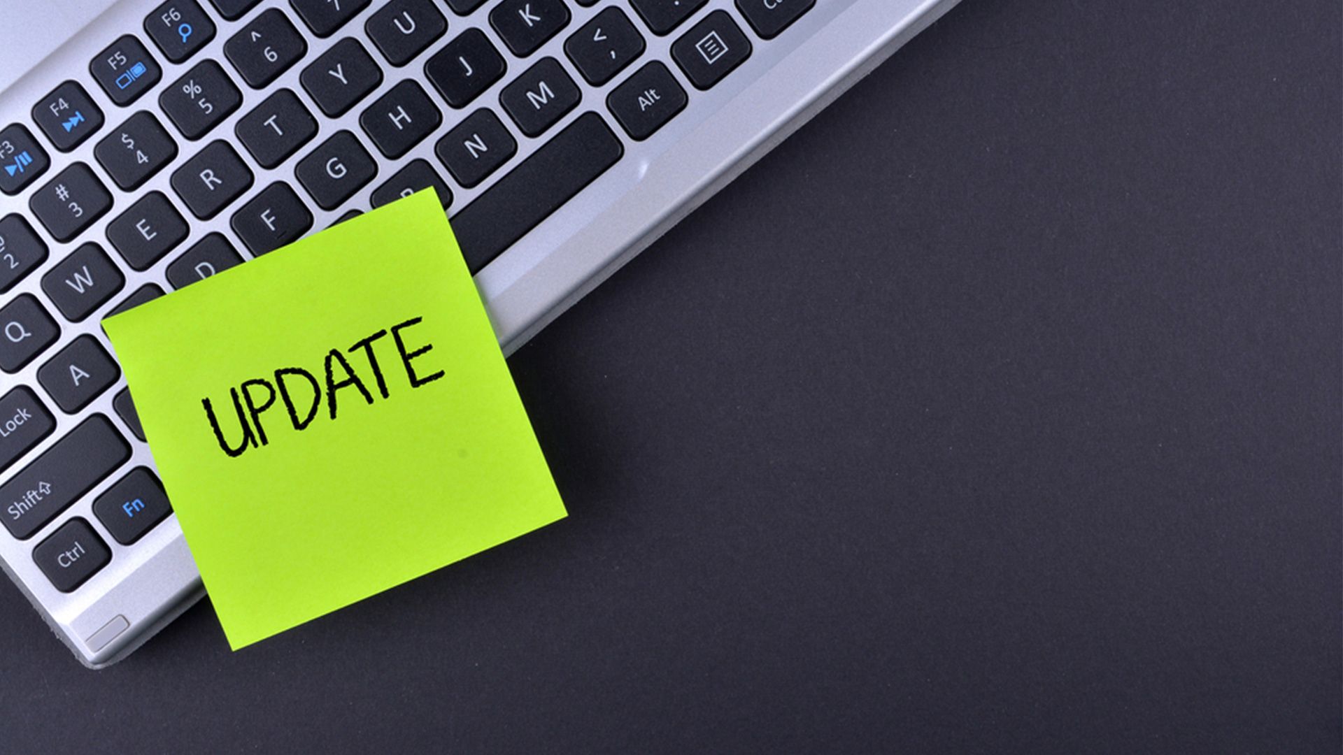 "Update"- Post-It klebt auf einer Laptop-Tastatur