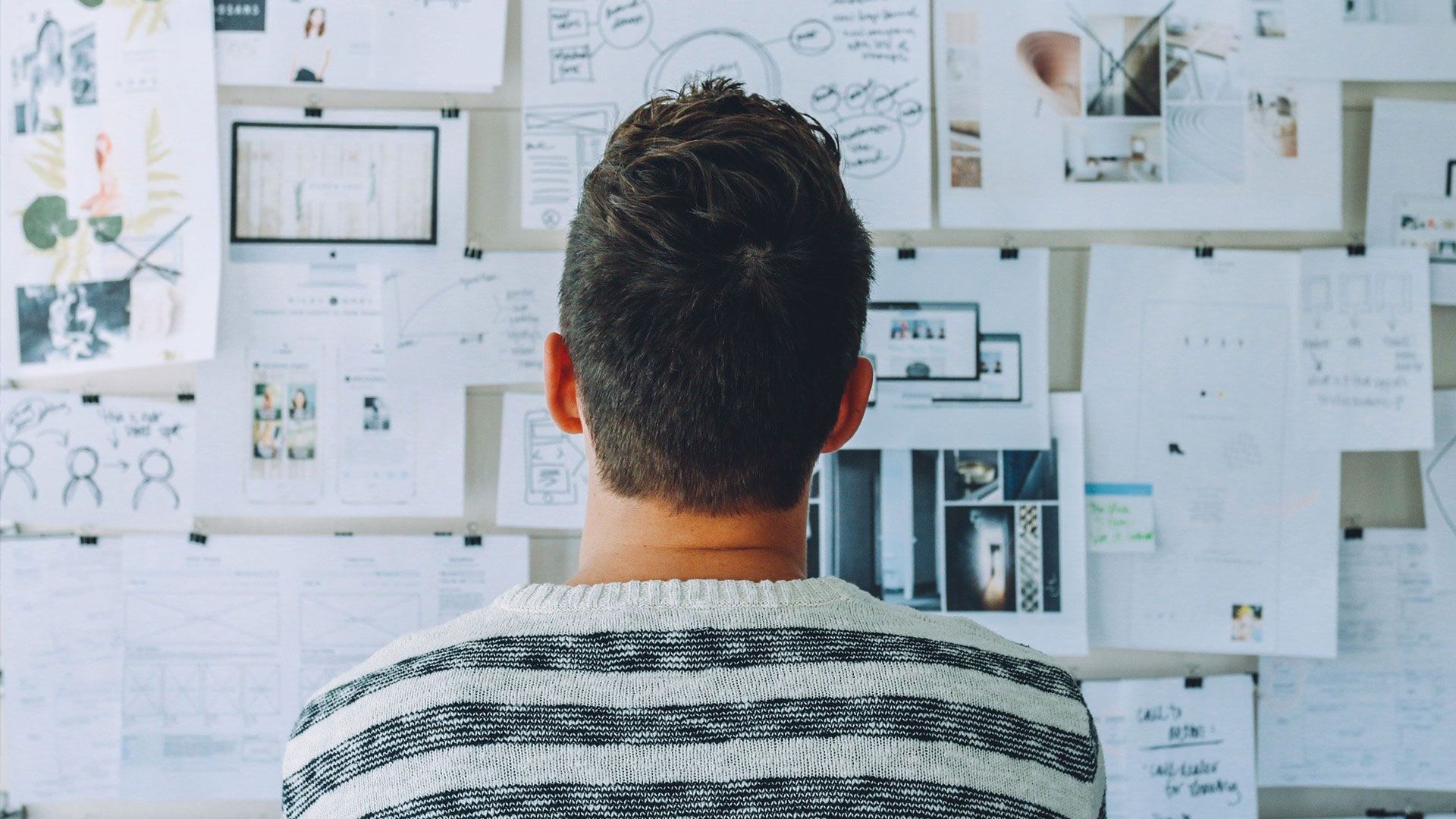 Mann vor einer Wand mit Dokumenten stehend