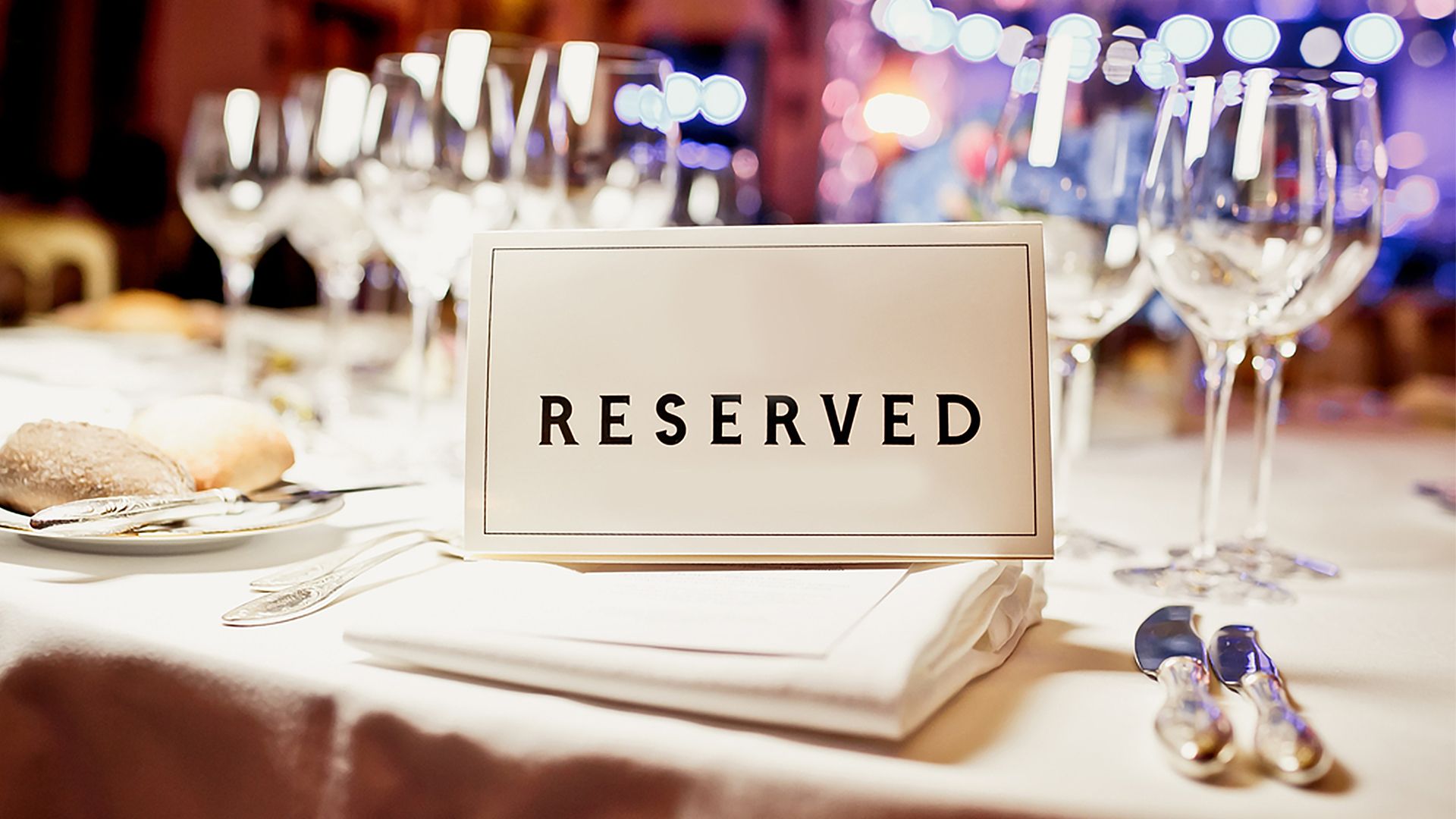 Ein Tischkärtchen mit der gedruckten Aufschrift "Reserved" auf einem gedeckten Tisch.