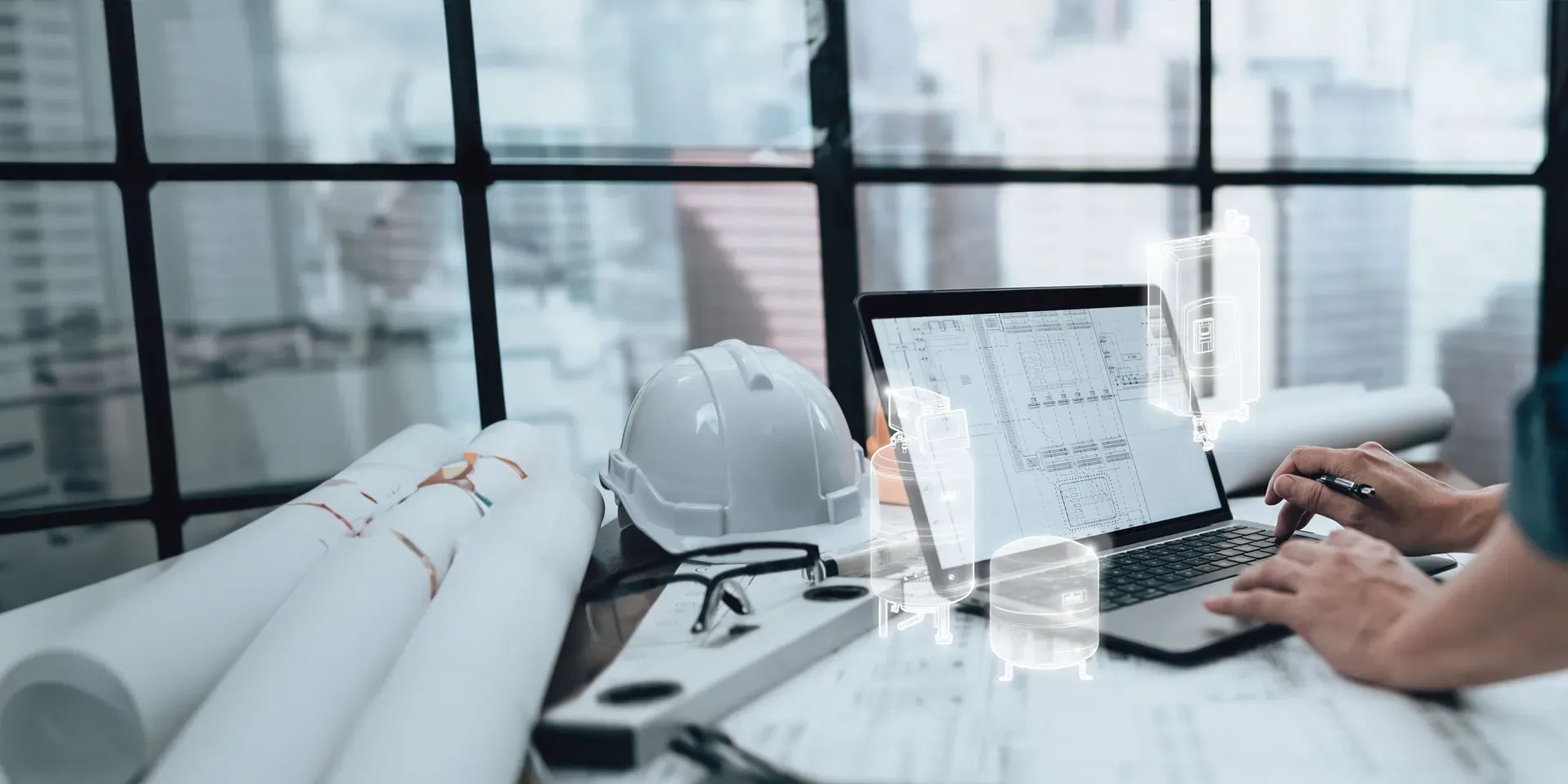 Person, die an einem Laptop mit Architekturplänen arbeitet, einen Schutzhelm und Zeichenutensilien auf einem Schreibtisch hat und durch große Fenster auf eine Stadtlandschaft blickt.