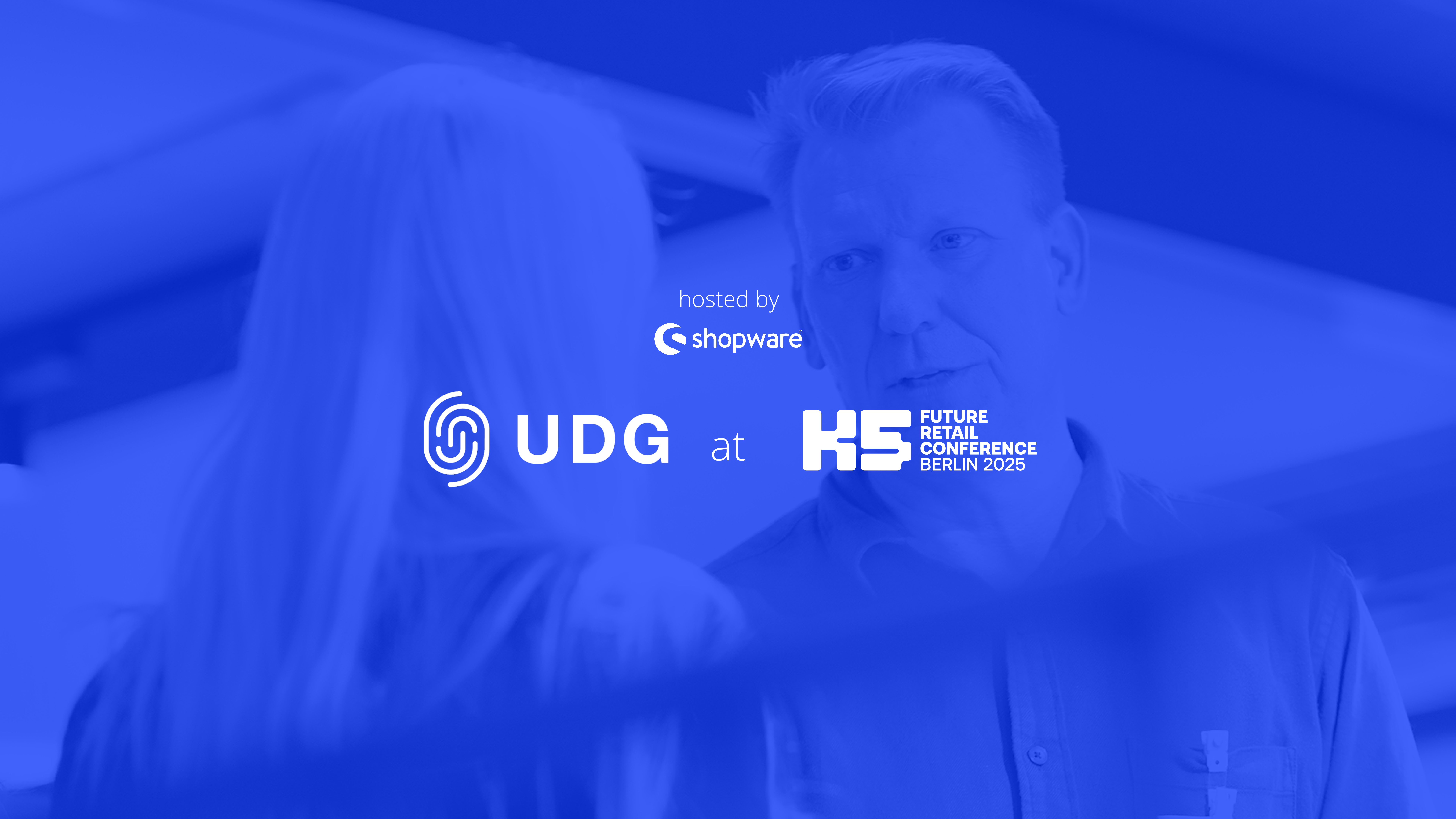 Ein blau getöntes Bild mit zwei Personen im Gespräch auf der K5 Future Retail Conference Berlin 2025 mit UDG und Shopware.